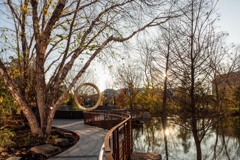 Golden hour lighting over a garden with water to the side.