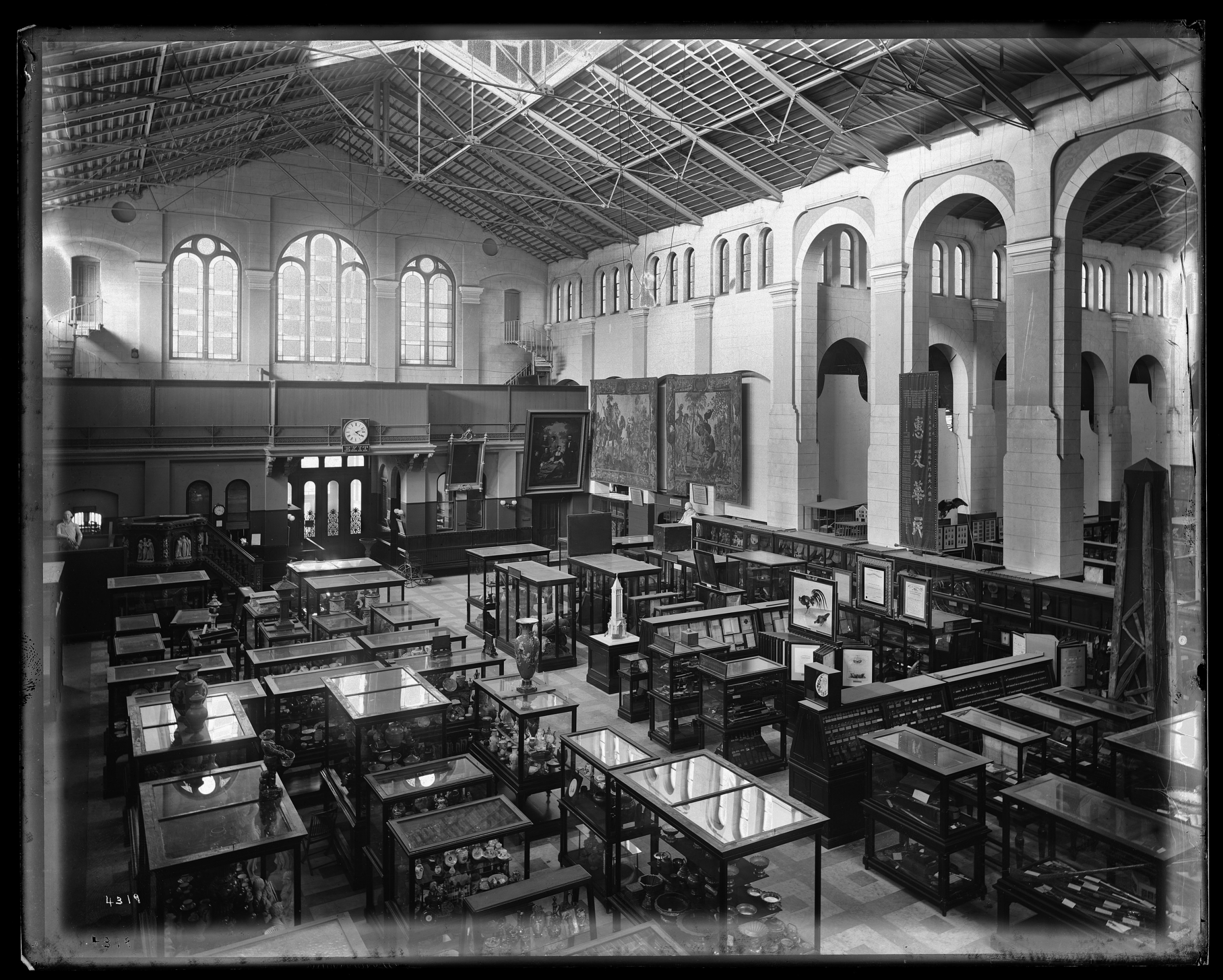 Large room with high ceilings and windows. Its floor is filled with exhibit cases.