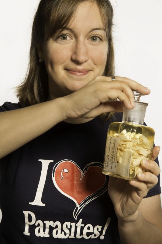 woman holding jar of parasites while wearing an I heart parasites shirt