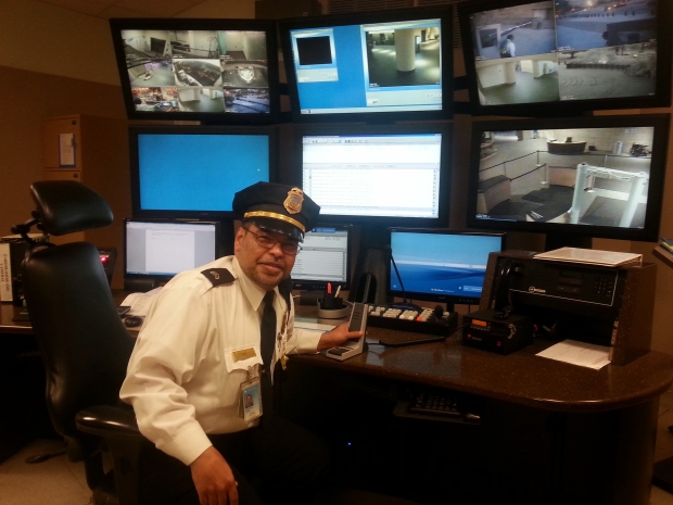 Man wearing a uniform sits in front of the control room computers. 