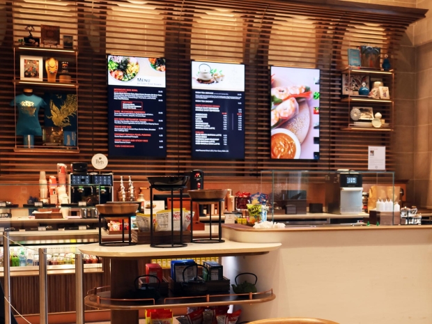 A coffee shop counter with wood cabinets, warm lighting and snack options on display.