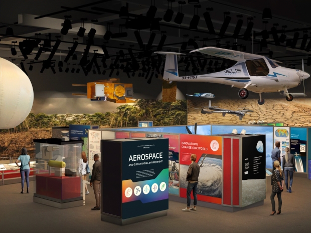 Digital rendering of a museum exhibition with colorful text panels and large stationary and hanging objects 