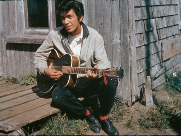 Vintage photo of a man playing a guitar on a porch 