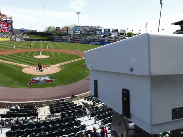 A white camera installed in a baseball stadium overlooking the field.