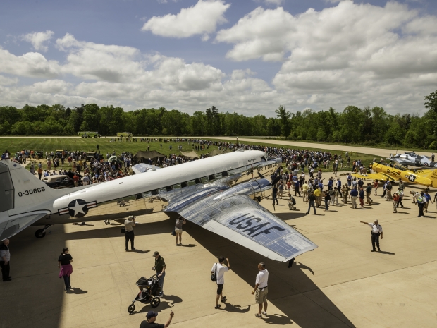 Outdoor image of people walking around a tarmac with parked planes on a sunny day. 