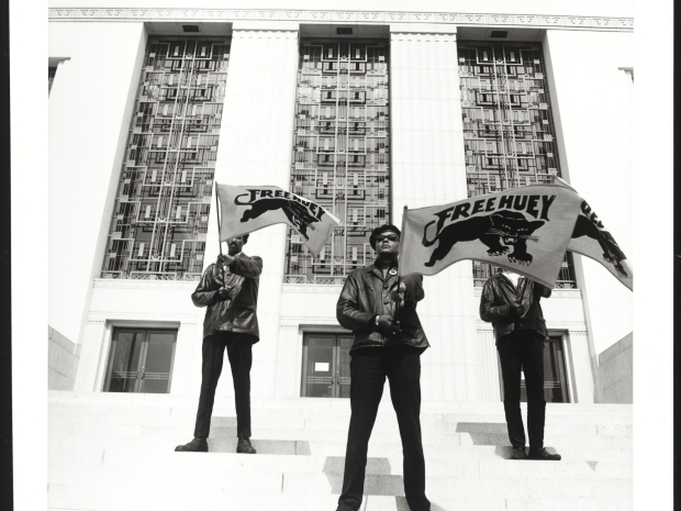 Three men stand with arms crossed