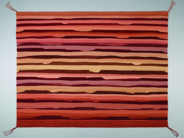 Image of flat tapestry with horizontal stripes in varying shades of orange, yellow, pink and red.