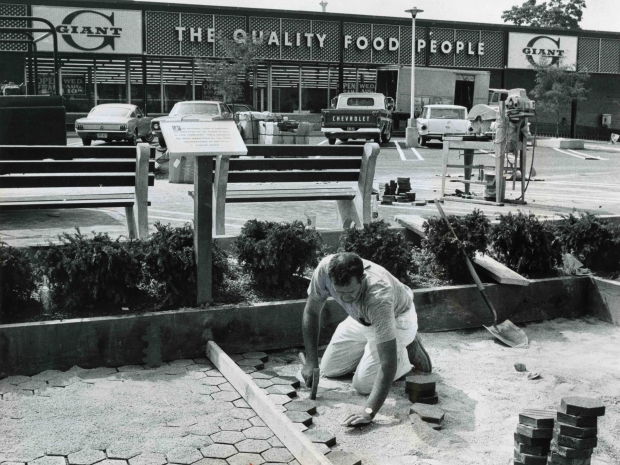 Man repairing road in front of supermarket