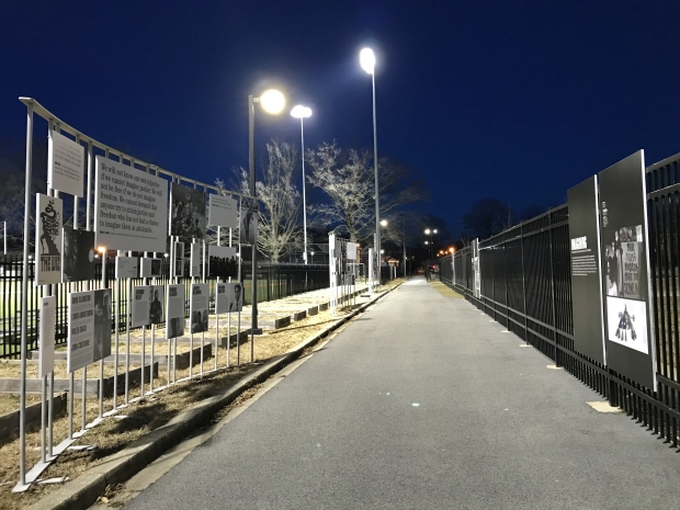 Empty street lined with posters attached to fences on each side 