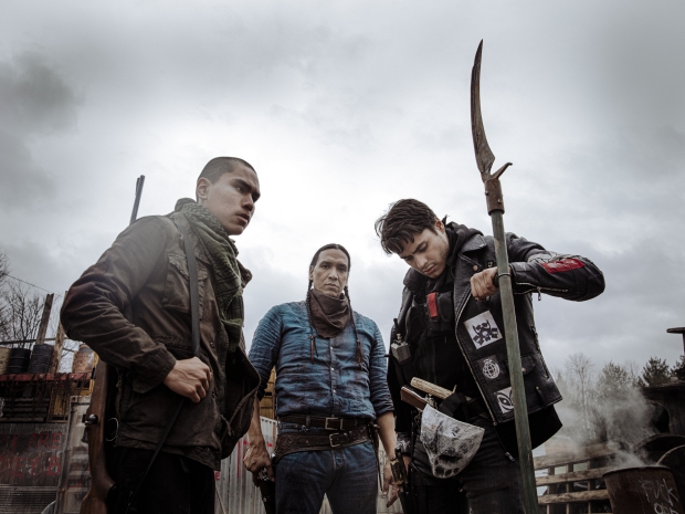 Three armed Native men, one staring into camera