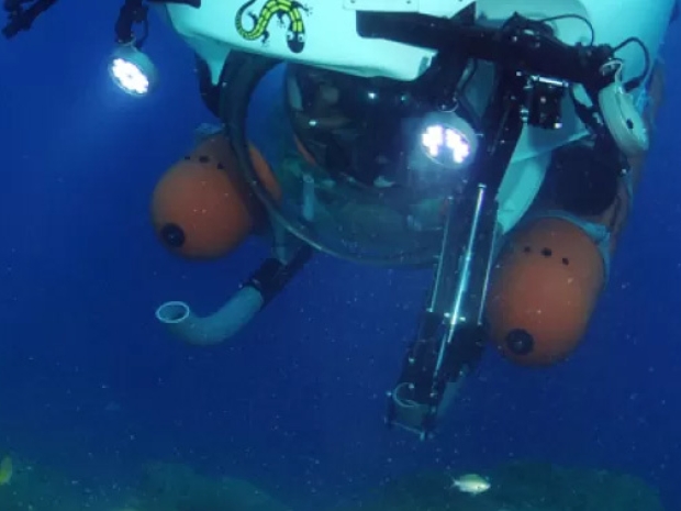 White and orange sub with large glass window underwater. 