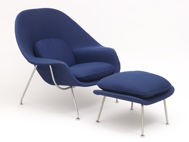 Blue, open, shell-like chair upholstered in fabric, resting on chrome legs.