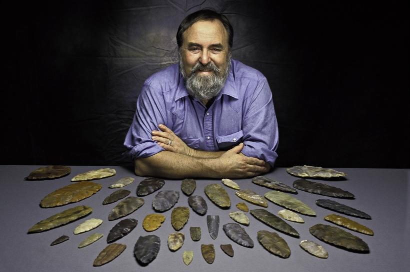 man at table with Clovis stone points spread in front of him