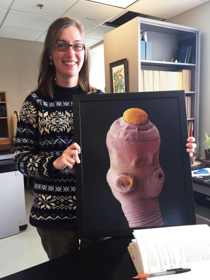 Woman holding an image of a tapeworm.