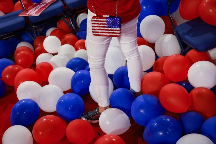 woman with American flag purse surrounded by red and blue balloons