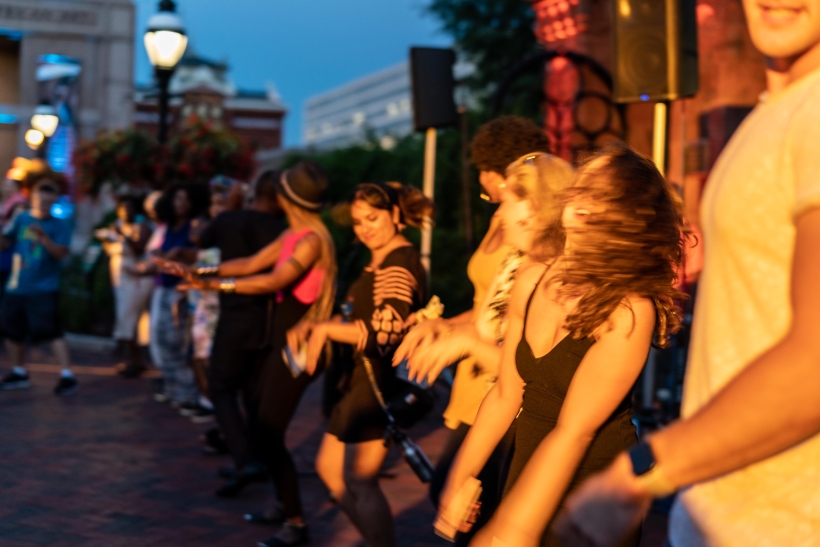 People dancing in a line at dusk.