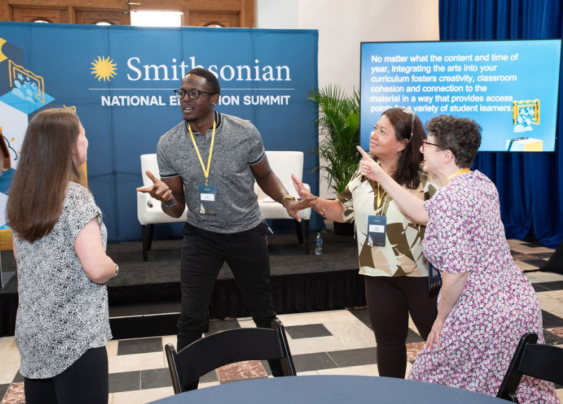 A group of educators pose in front of a conference poster