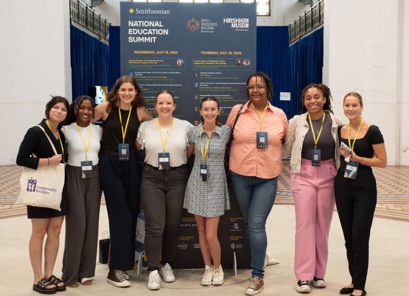 A group of educators pose in front of a conference poster